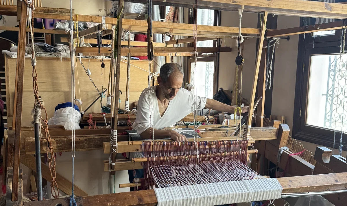 A weaver at work on a large loom in Tangier, weaving thread by hand.