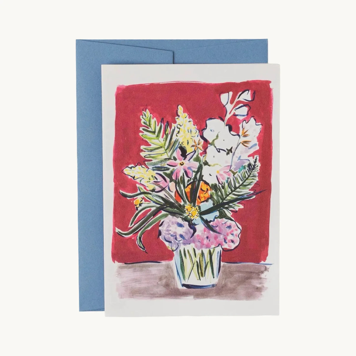 Greeting card of pink and lilac flowers, yellow blossoms and ferns in a glass vase on a deep red background, with a blue envelope