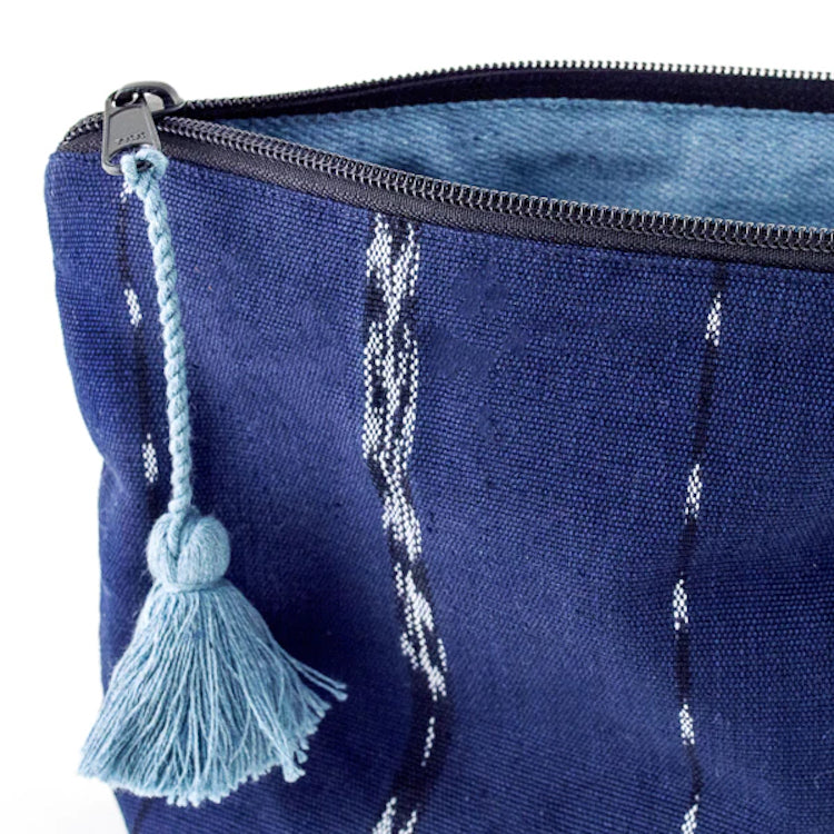 The Voyage Dubai - Nella Zipper Pouch - Indigo Keep cosmetics and other necessities organised and ready to grab and go with the versatile Nella pouch. Made from handwoven indigo and jaspe (ikat) fabric, woven on a traditional foot loom and finished with a recycled denim lining and blue tassel.