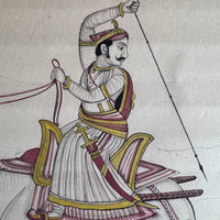 Close-up of a Maharaja in a turban raising a spear, seated on a gold and maroon saddle, painted on old paper