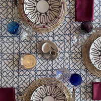 Blue Pagoda slate blue lattice block print tablecloth set for three with rattan chargers, burgundy napkins and a small tray of salt in the centre