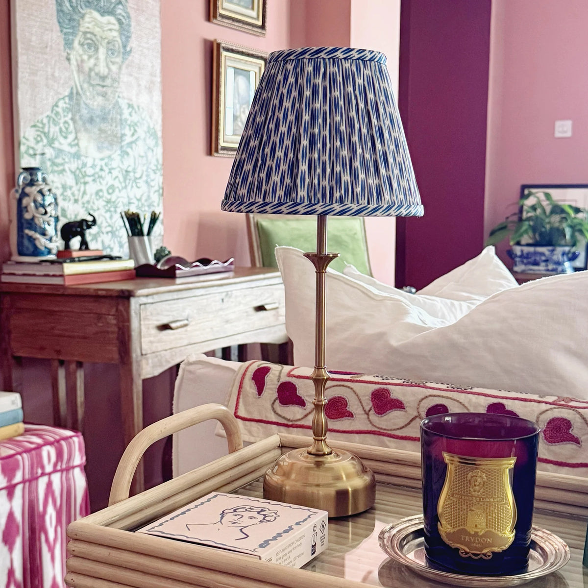 The Voyage Dubai - Cordless Antique Gold Table Lamp with Blue Ikat Shade - Rechargeable iron table lamp. Styled on a rattan tray beside a candle.