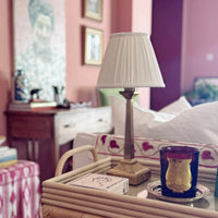 The Voyage Dubai - Cordless Antique Gold Table Lamp with White Pleated Shade - Rechargeable iron table lamp. Styled on a rattan tray, closer view of the square beaded base.