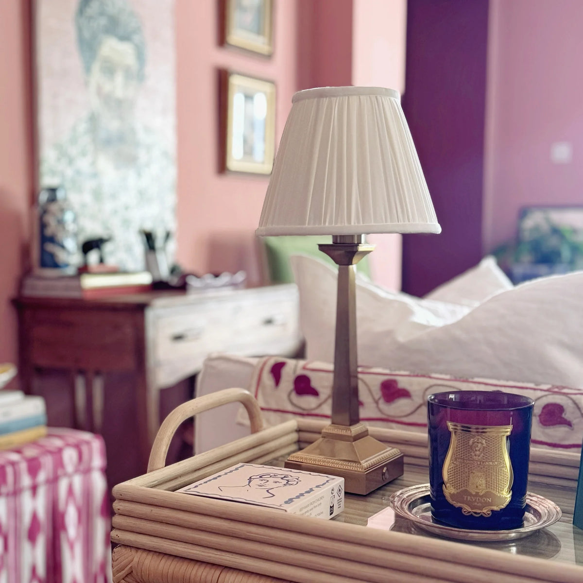 The Voyage Dubai - Cordless Antique Gold Table Lamp with White Pleated Shade - Rechargeable iron table lamp. Styled on a rattan tray, closer view of the square beaded base.