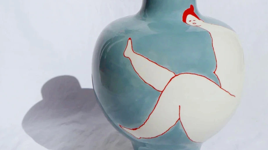 Laetitia Rouget Queen Blue Vase — hand-painted ceramic with reclining female figure in red, photographed against white linen