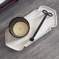 Top view of the marble tray on a wooden table holding a candle and a black wick trimmer