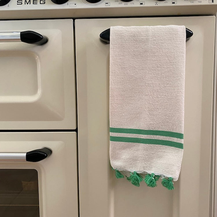 The Voyage Dubai - Made in Tangier Jibli Hand Towel - Green  Hand woven in Morocco from 100% pure cotton, the Jibli Hand Towel in double stripe is a great way to add a pop of colour to a guest bathroom, drinks cart or kitchen. The towels are finished with a fringe of pom poms and are made from a wonderfully soft yet highly durable handwoven cotton, making them perfect for everyday use.   Use as table napkins, tea towels or hand towels.