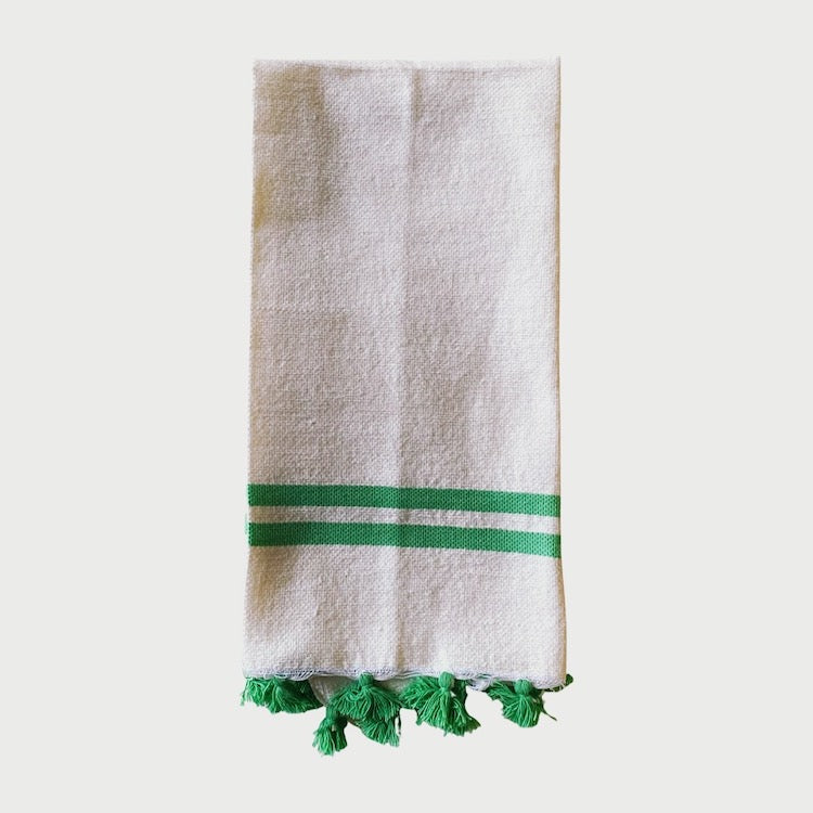The Voyage Dubai - Made in Tangier Jibli Hand Towel - Green  Hand woven in Morocco from 100% pure cotton, the Jibli Hand Towel in double stripe is a great way to add a pop of colour to a guest bathroom, drinks cart or kitchen. The towels are finished with a fringe of pom poms and are made from a wonderfully soft yet highly durable handwoven cotton, making them perfect for everyday use.   Use as table napkins, tea towels or hand towels.