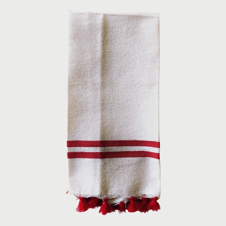 The Voyage Dubai - Made in Tangier Jibli Hand Towel - Red  Hand woven in Morocco from 100% pure cotton, the Jibli Hand Towel in double stripe is a great way to add a pop of colour to a guest bathroom, drinks cart or kitchen. The towels are finished with a fringe of pom poms and are made from a wonderfully soft yet highly durable handwoven cotton, making them perfect for everyday use.   Use as table napkins, tea towels or hand towels.