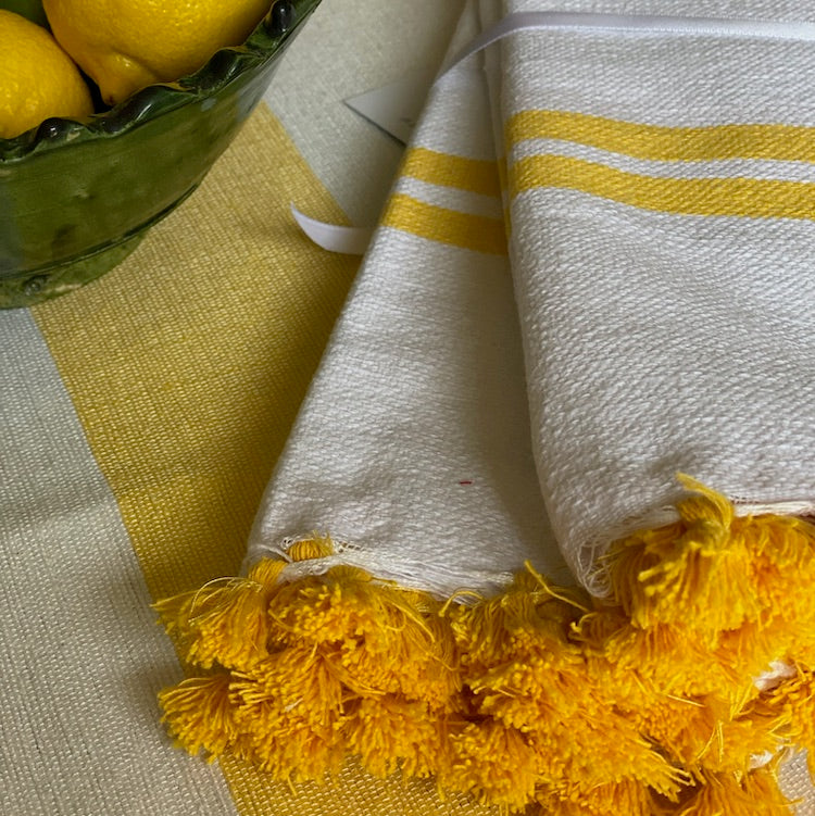 The Voyage Dubai - Made in Tangier Set of 6 Jibli Napkins - Buttercup Inspired by the Jibli (country) women of Northern Morocco these generously sized table napkins add an element of fun to any table. Available in pure white cotton, as well as fun colourful stripes on a creamy white base, each napkin is finished with matching pom poms. Use as table napkins, tea towels or hand towels.