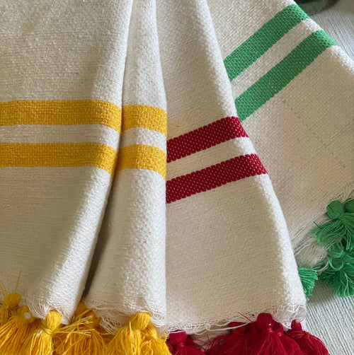 The Voyage Dubai - Made in Tangier Jibli Hand Towel - Yellow  Hand woven in Morocco from 100% pure cotton, the Jibli Hand Towel in double stripe is a great way to add a pop of colour to a guest bathroom, drinks cart or kitchen. The towels are finished with a fringe of pom poms and are made from a wonderfully soft yet highly durable handwoven cotton, making them perfect for everyday use. 